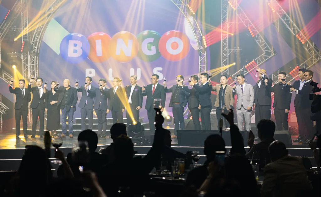 Executives raise a toast on a lit stage beneath the BingoPlus logo as guests look on at BingoPlus Night
