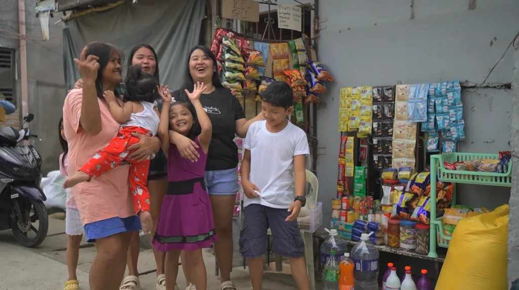 Family laughs outside the sari-sari store granted to Donna by BingoPlus Foundation's Make-A-Wish Project