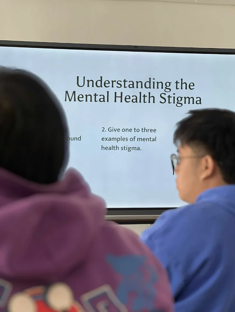 Participants watch a presentation slide reading Understanding the Mental Health Stigma during a training session