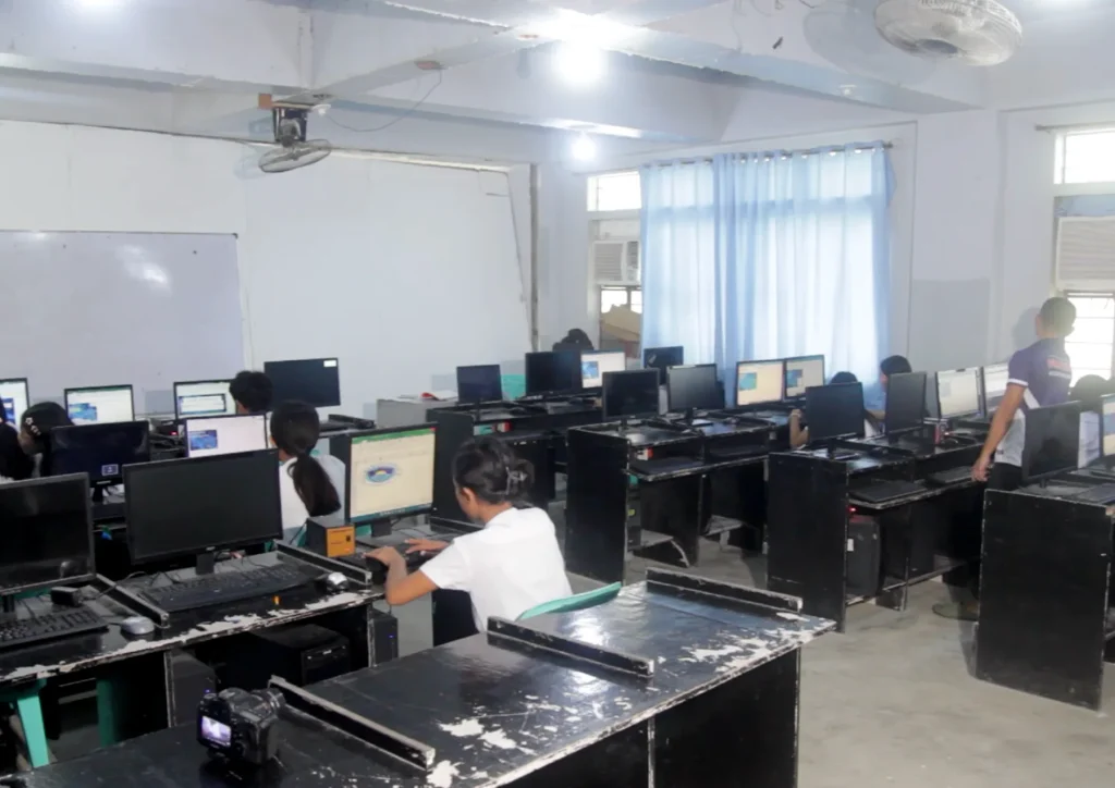 Students work at desktop computers in an older school computer room