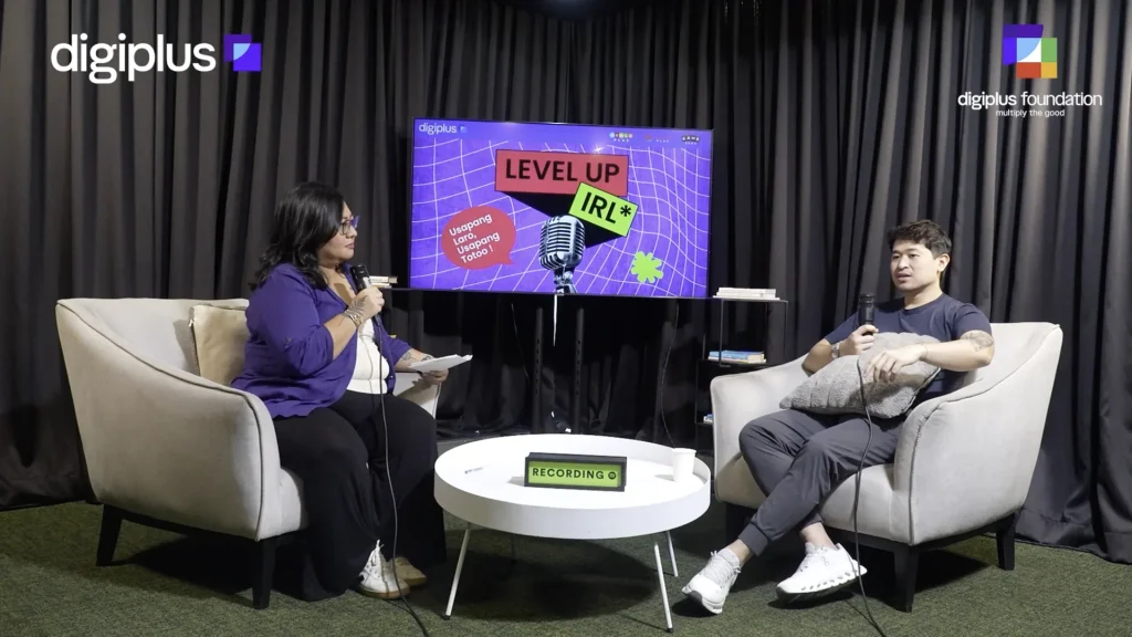 Host Cia Hermosa Jorge interviews guest Flo Campomanes on the Level Up IRL podcast set, a recording sign on the table