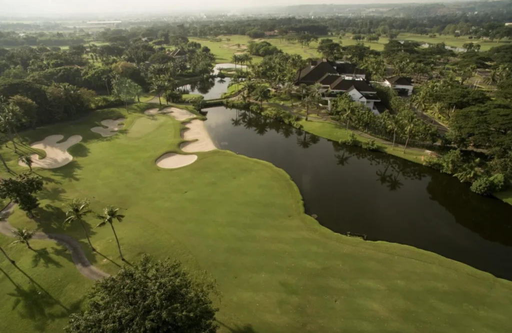 Manila Southwoods Aerial view of a golf course with sand bunkers, a lake and a clubhouse among palm trees