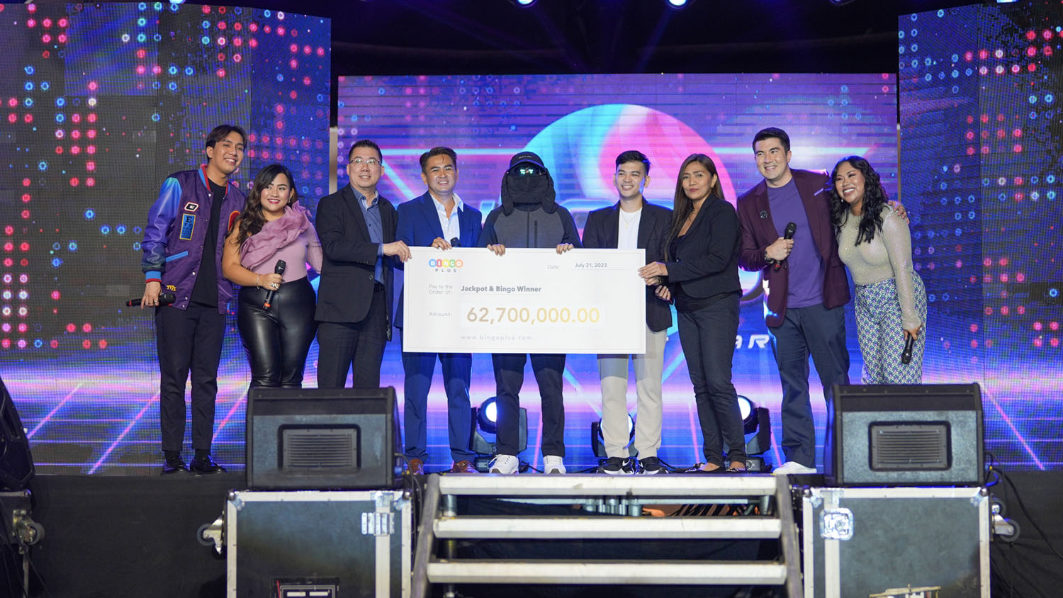 BingoPlus hosts and jackpot winner on stage with a 62,700,000 peso cheque